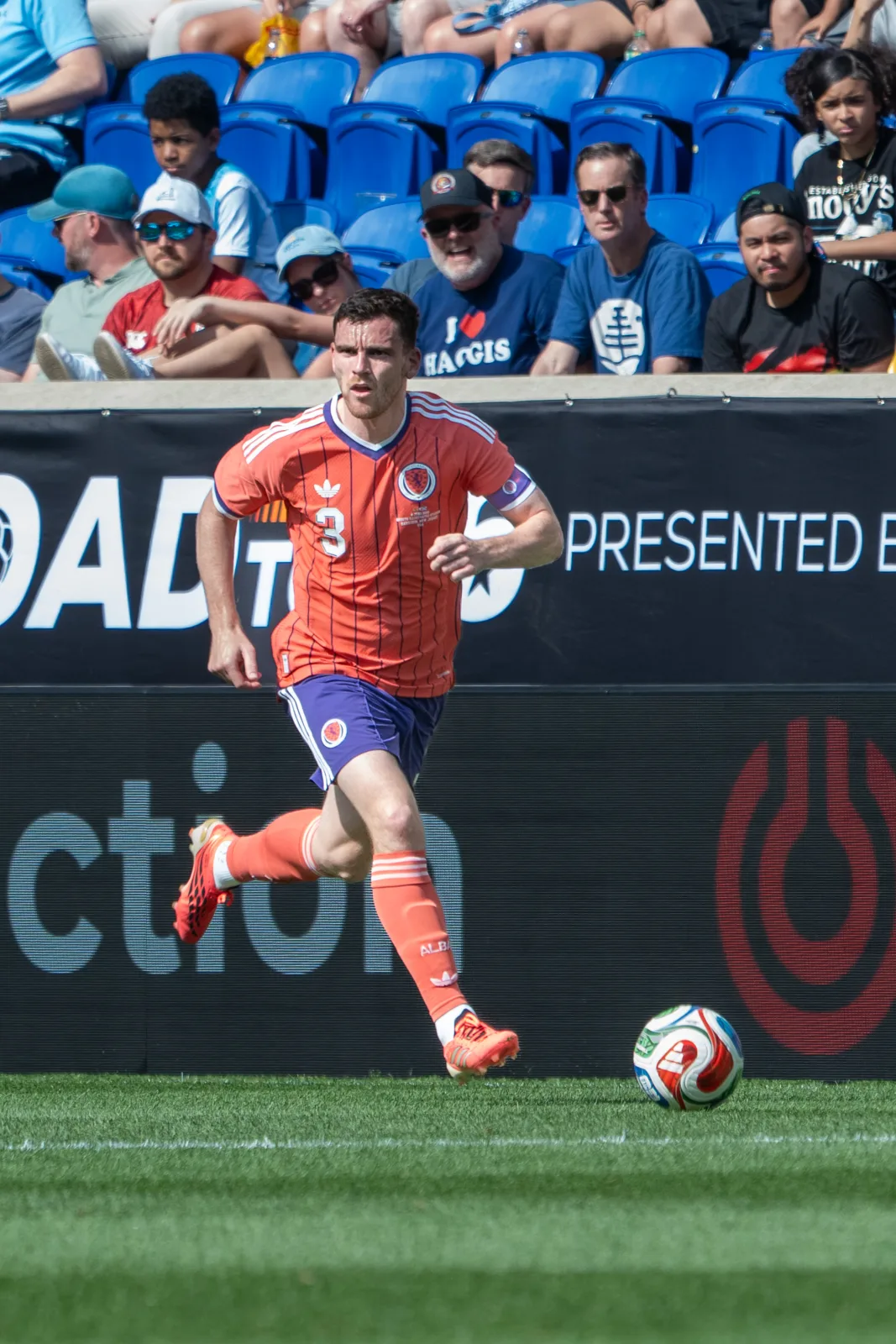 Scotland captain Andy Robertson running with the ball in the Scotland orange away kit, wearing the captain's armband, during Scotland v Bolivia on 6 June 2026.